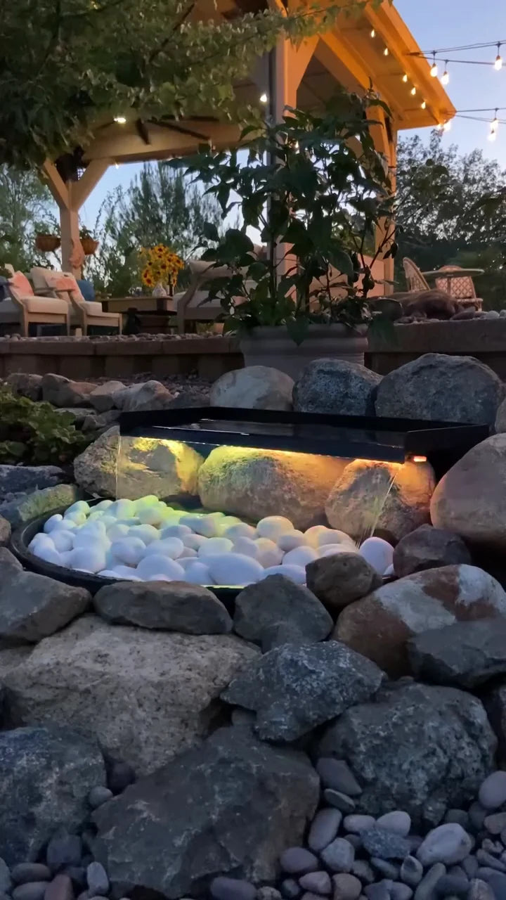 Warm multicolored light glows across the completed waterfall at dusk.